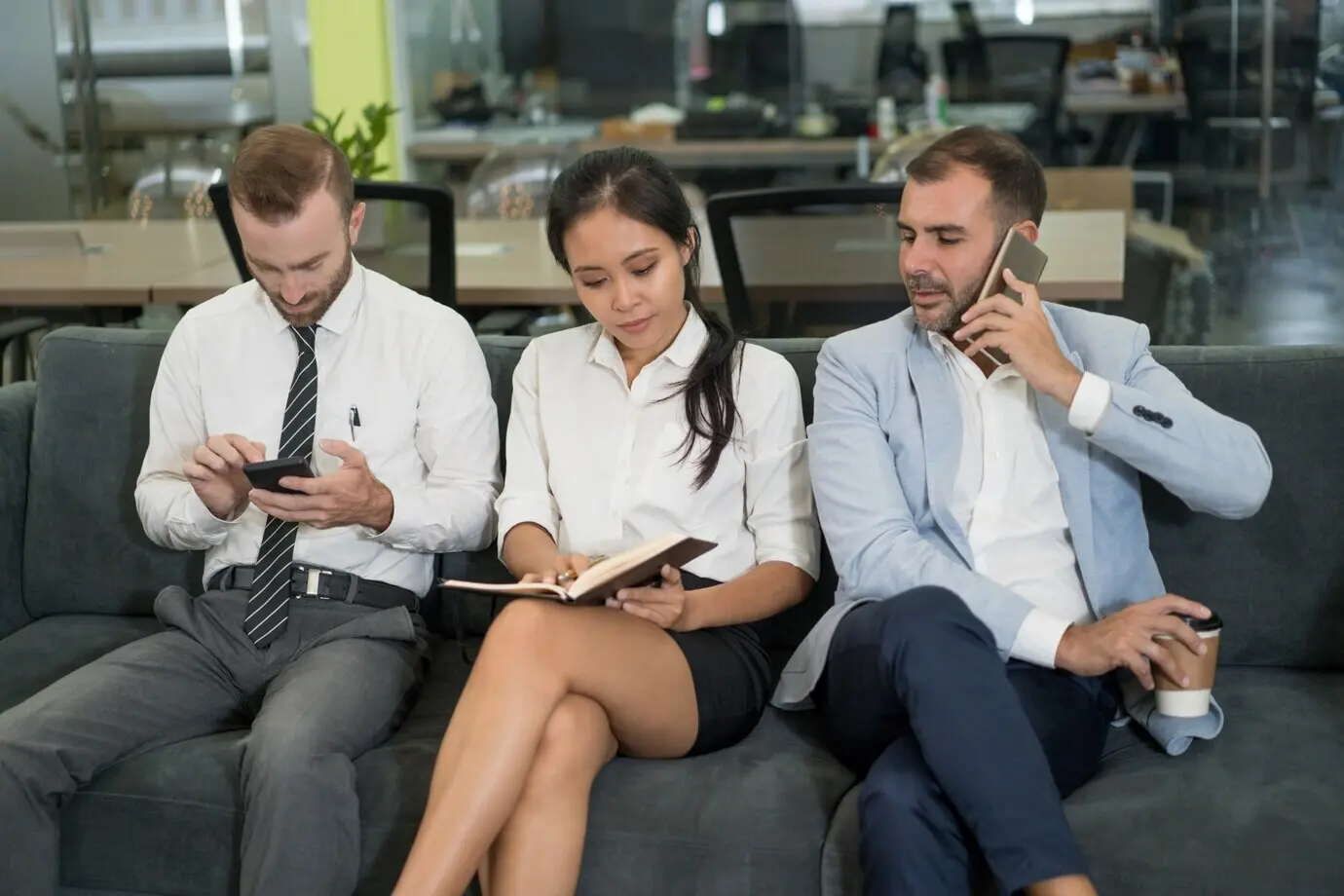 Geschäftsleute sitzen auf einem Sofa und machen eine Kaffeepause.